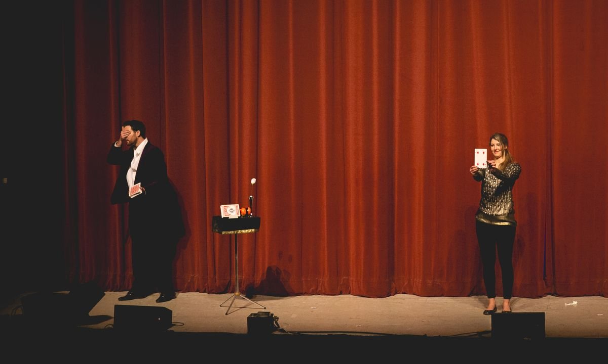 Fernando Mier adivinando a ciegas la carta que sostiene una voluntaria