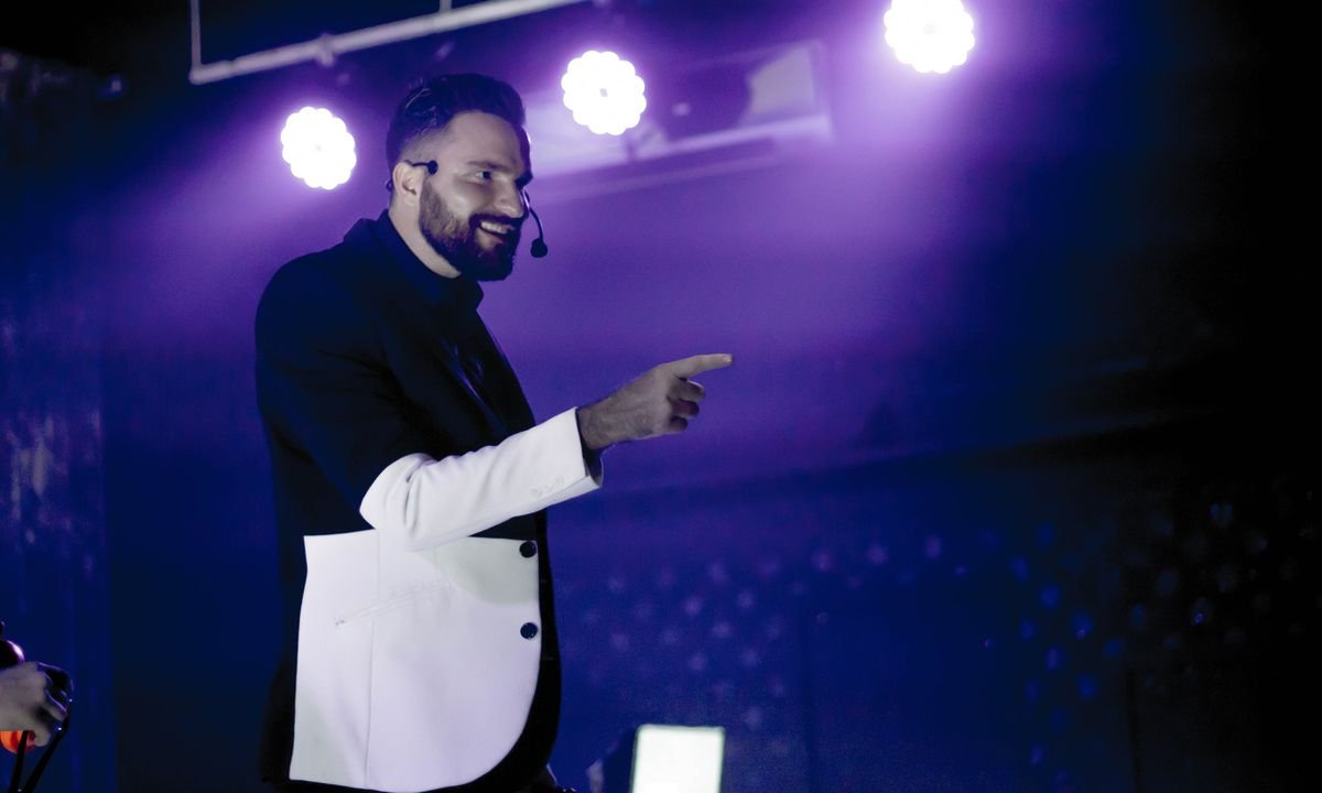 Fernando Mier señalando al público durante un show con iluminación morada