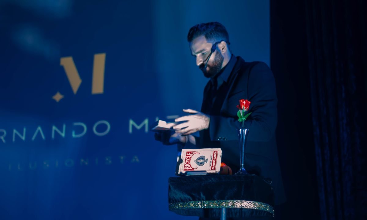 Fernando Mier con una baraja frente a su logotipo proyectado en el escenario