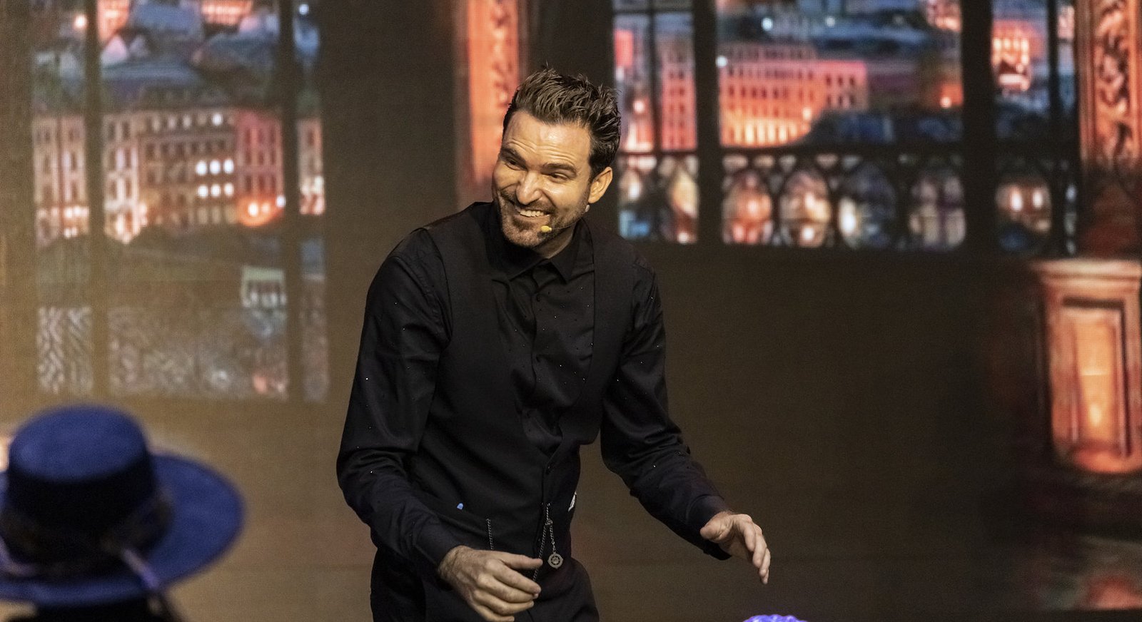 Fernando Mier en escena durante un evento corporativo, con ventanales iluminados al fondo